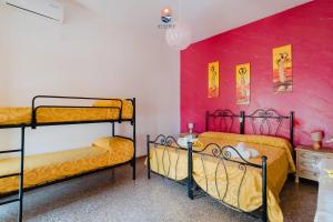 2 Etagenbetten in einem Zimmer mit einer rosa Wand in der Unterkunft Dimora Lucy by Vivimy in Taviano