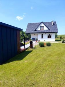 a white house with a black roof and a yard at OdpocznieszTU in Brzozowa