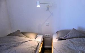 a bedroom with two beds and a light on the wall at Hempen Fied Gästehaus - Apartment 4 in Bad Zwischenahn