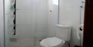 a white bathroom with a toilet and a shower at Studio em São José SC in São José