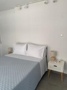 a bedroom with a bed with white sheets and a nightstand at Marianna's penthouse at Exarcheia square in Athens