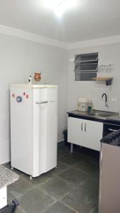 a kitchen with a white refrigerator and a sink at Sua Praia seu lar in Itanhaém +15 photos