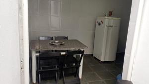 a small kitchen with a table and a refrigerator at Sua Praia seu lar in Itanhaém