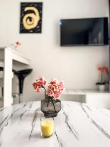 a vase with flowers and a glass of orange juice at Piscina Mare #PROPERTLY in Nea Kallikrateia +45 photos