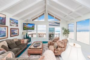 a living room with a couch and chairs and a tv at 7Br Beachfront Retreatstunning Ocean Views & Walkable Fun By Beachview Rentals in Newport Beach