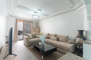 a living room with a couch and a tv at Maison soleil - Appartement pour famille in Marrakech
