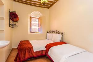 1 Schlafzimmer mit 2 Betten, einem Waschbecken und einem Fenster in der Unterkunft Hotel Atlas in Marrakesch