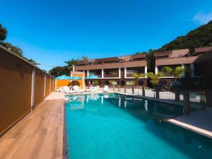 einen Pool mit Tischen und Stühlen vor einem Gebäude in der Unterkunft Casas Aconchegantes a 600m da Praia de Paúba in São Sebastião