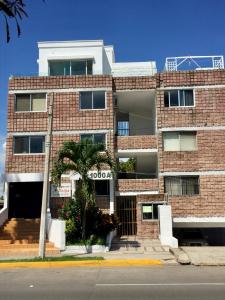 a brick building with a palm tree in front of it at Excelente apto muy cerca de la playa 202 in Mazatlán