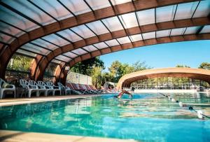 a person swimming in a pool under a bridge at Bungalow Lodge 2 chambres in Lège-Cap-Ferret +10 photos