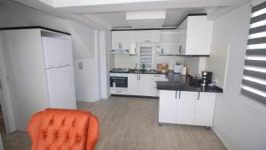 a kitchen with white cabinets and a orange chair in it at Oludeniz Villa with Private Pool in Fethiye
