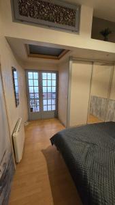 a bedroom with a bed in a room with windows at Le treport - centre - Plain-pied 1 chambre in Le Tréport