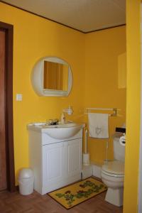 a yellow bathroom with a sink and a toilet at Pension B&B Dodeman in Saint-Pierre