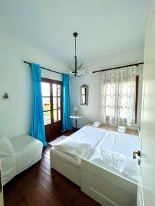 a bedroom with a large white bed and blue curtains at Electra Beach House in Chorefto