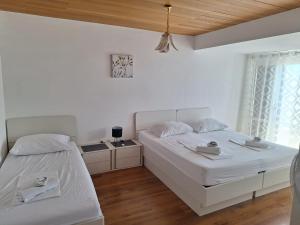 two beds in a bedroom with white walls and wood floors at Apartments Dalmacija in Podstrana