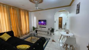 a living room with a black couch and a tv at DRE'S WORLD STAYs in Mombasa