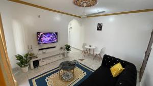 a living room with a couch and a tv on a wall at DRE'S WORLD STAYs in Mombasa +3 photos