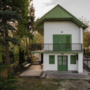 a house with a green door and a balcony at Napbogár Vendégház in Balatongyörök