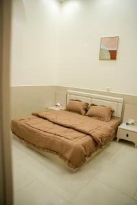 een bed in een witte kamer met een bedframe bij شقق قلب العاصمة in Bagdad