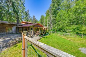 a house with a fence in front of a yard at 5 Mi to Mt Rainier Natl Park Cozy Cabin with Deck! in Ashford