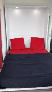 a bed with two red pillows on top of it at Studio vue panoramique-centre ville in La Grande-Motte