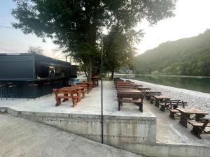 a row of wooden tables and benches next to a river at Drinsko Srce Tegare in Bratunac