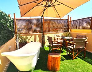 a table and chairs and an umbrella on a patio at Old Town Rhapsody, Cosy 2-Floor Home with Rooftop Bathtub, BBQ & Lounge Under Sun Umbrellas in Rethymno