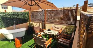 a bath tub and an umbrella with a table and chairs at Old Town Rhapsody, Cosy 2-Floor Home with Rooftop Bathtub, BBQ & Lounge Under Sun Umbrellas in Rethymno