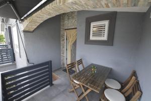 a table and chairs on a porch with a window at Apartmani Vesna in Vir