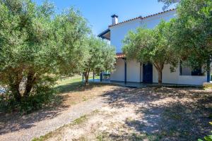 a white house with trees in front of it at Hillside Hideaway in Paliouri