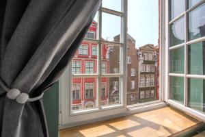 een groot raam met uitzicht op een rood gebouw bij Black Swan House, Old Town in Gdańsk +48 foto's