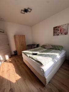 a bedroom with a bed and a wooden floor at A&B Ferienwohnungen in Rosenheim