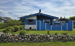 a blue and white house with a rock fence at Ferienhaus Küstenzauber Simonsberg Nordsee Meer Husum in Simonsberg