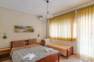 a bedroom with a bed and a couch and a window at Ikaros Apartments in Paralia Katerinis +38 photos