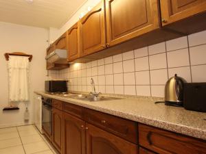 a kitchen with wooden cabinets and a sink at Reihenhäuser in Strackholt in Strackholt +28 photos