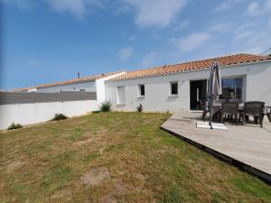 a patio with a table and an umbrella on a deck at Les pivoines Notre-Dame-de-Monts in Notre-Dame-de-Monts