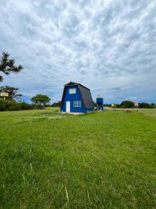 a blue house in a field of green grass at Alquiler en Chapadmalal en el barrio "El Marquesado" in San Eduardo del Mar