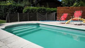 a swimming pool with two chairs and a swimming pool at Cabañas Ananda in Villa Ventana