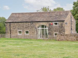 a brick building with a large window in a field at Bullace Barn in Thurlstone