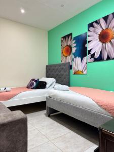 two beds in a room with flowers on the wall at hospedaje El patio in Salento