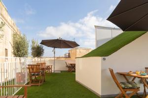 a patio with green grass and tables and an umbrella at Roel Boutique B&B in Cospicua