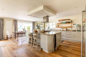 a kitchen with white cabinets and a island with bar stools at 5 Bedroom Family Friendly Beach House - a skip to the water! in West Wittering