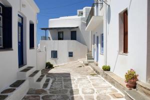 an alley with white buildings and a blue door at The Weaver's house in Kithnos