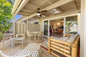 porche cubierto con sofá, mesas y sillas en Puamana 87-2 Premium Garden View, en Lahaina