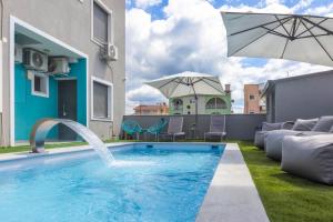 a swimming pool with a fountain and an umbrella at STREET 90 LuX APARTS in Keramoti