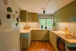a kitchen with green cabinets and a window at Röd Stuga by Falunio in Södertälje