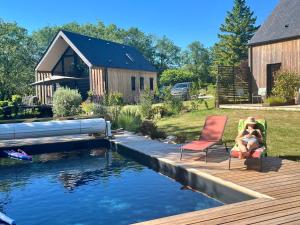 two people sitting in chairs on a deck next to a pool at Les Caminols in La Dornac +26 photos