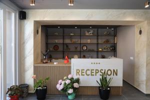 Una tienda con un cartel de recepción y flores al frente. en Kalpazo Hotel Tommy Durres, en ((Bishtkamzë ))