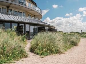 a building on the beach with tall grass at Seaside Double Duyn Suites in Callantsoog