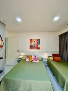 two beds in a room with green beds at Casas CostaMar in Caraguatatuba